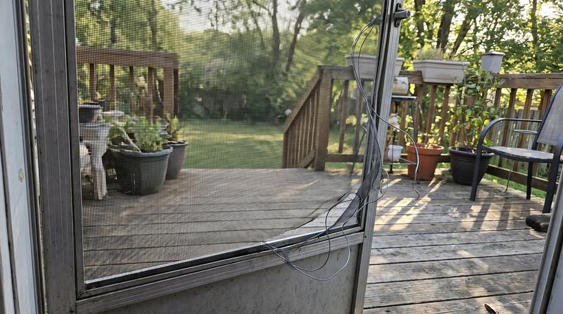 A sliding screen door with torn mesh before repair