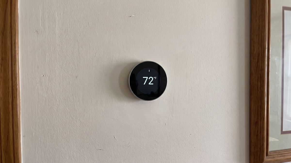 Round smart thermostat installed on a living room wall