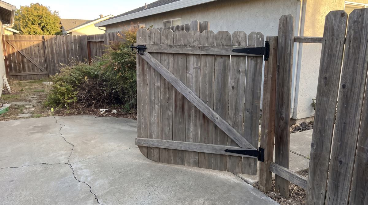 The same gate rehung level with new hinges and latch, same aged wood, closing cleanly