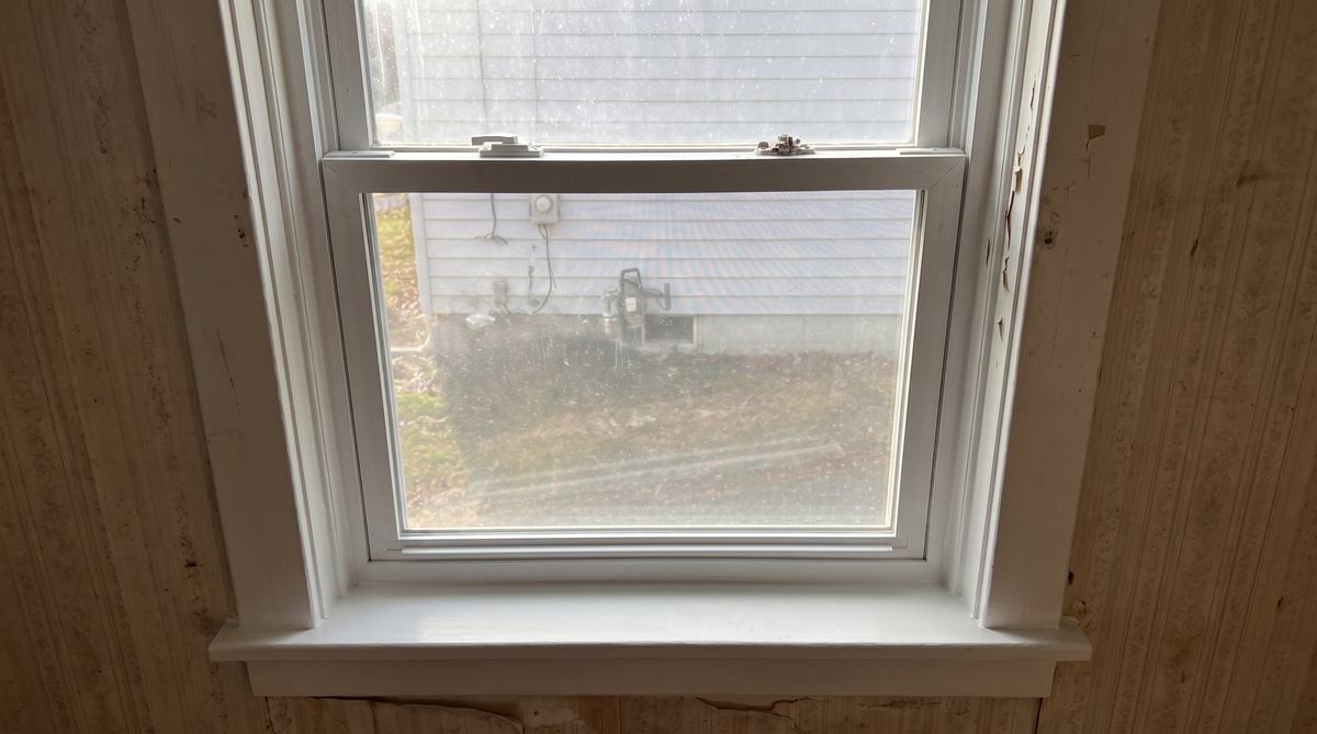 The same window repaired, sash staying up, sill rebuilt and painted, lock working
